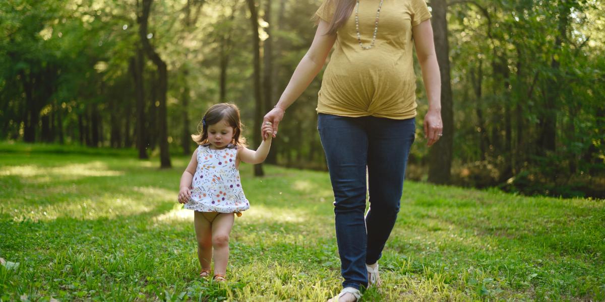A mother walking with her infant daughter at a park